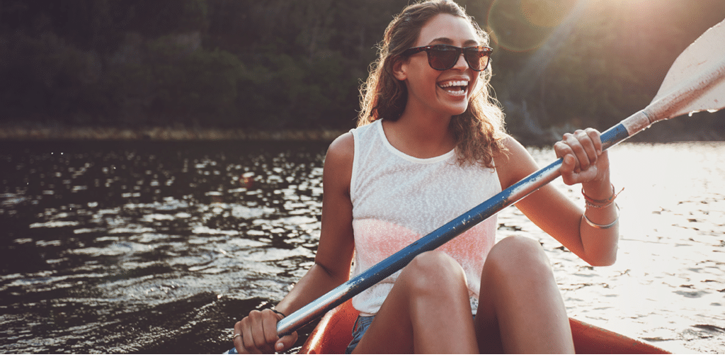 Smiling young woman kayaking on a lake  Happy young woman canoeing in a lake on a summer day 