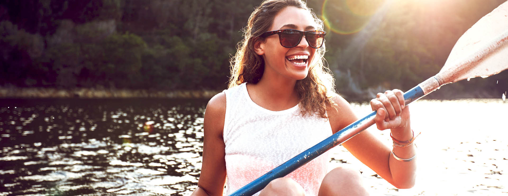 Smiling young woman kayaking on a lake  Happy young woman canoeing in a lake on a summer day 