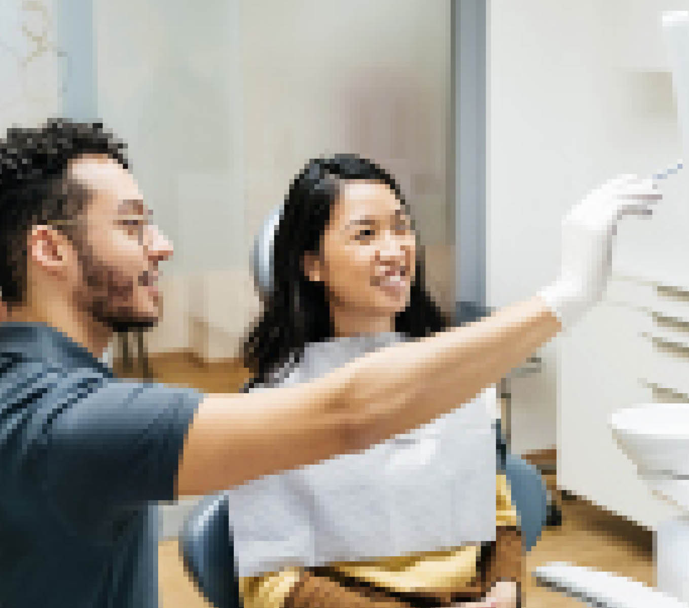 A young patient looking at a monitor and talking to her dentist about her dental health during a check up at his clinic.