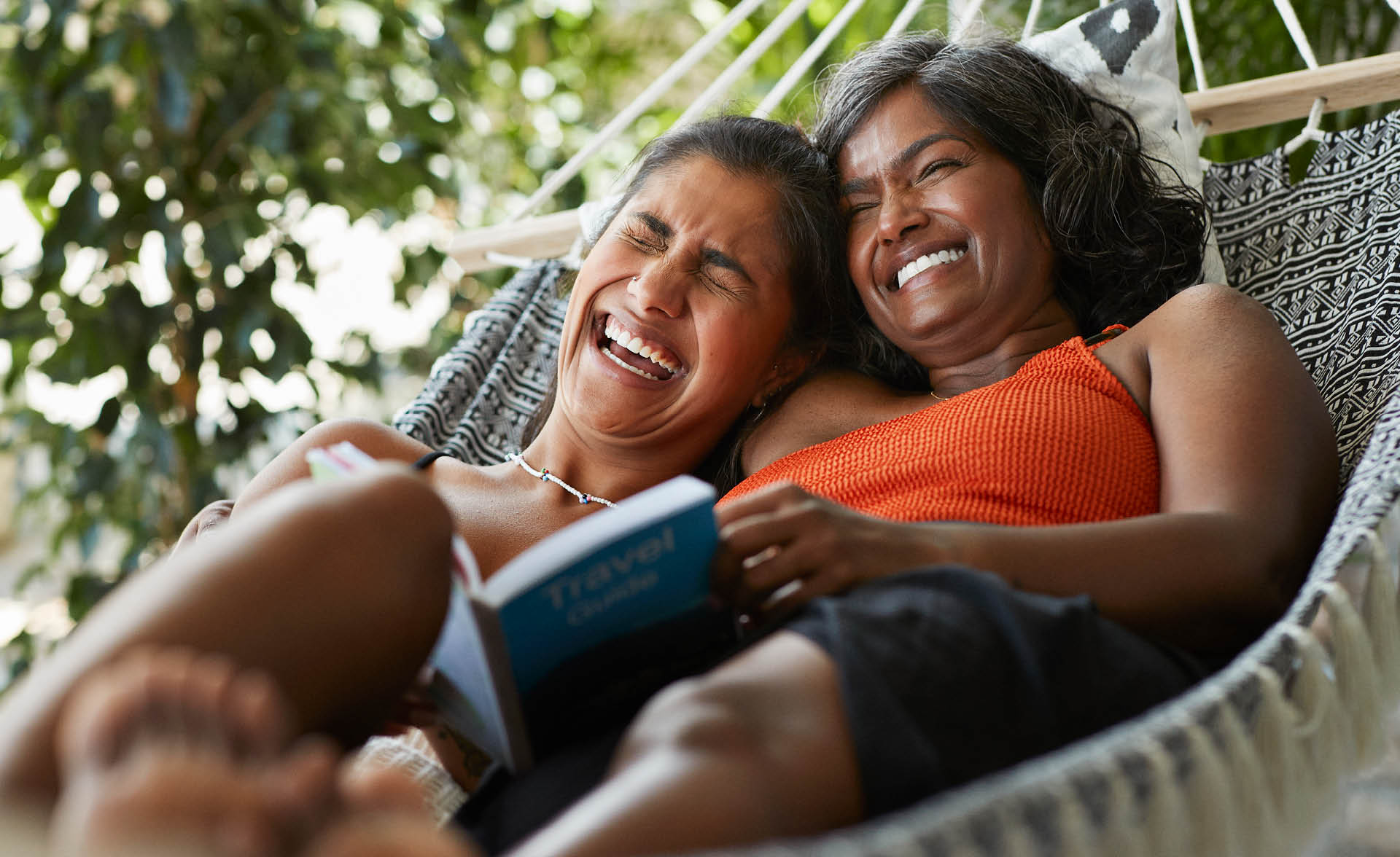 Mom and adult daughter laughing in hammock