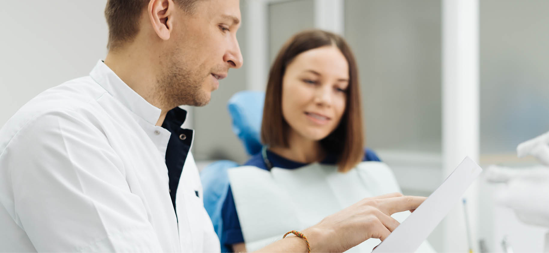 Male dentist talking to adult female patient