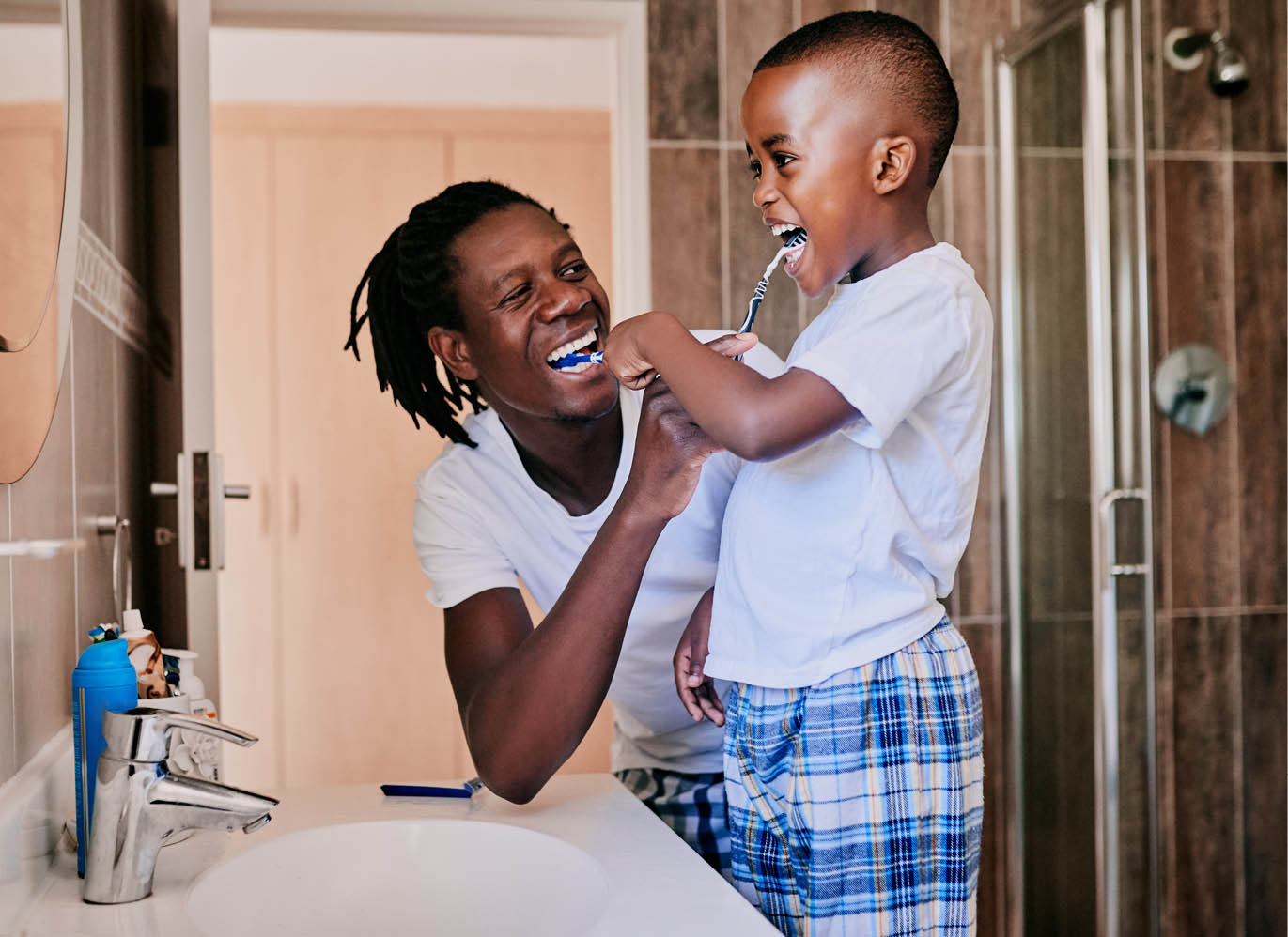 Cropped shot of a young man and his son brushing their teeth in the bathroom at home
