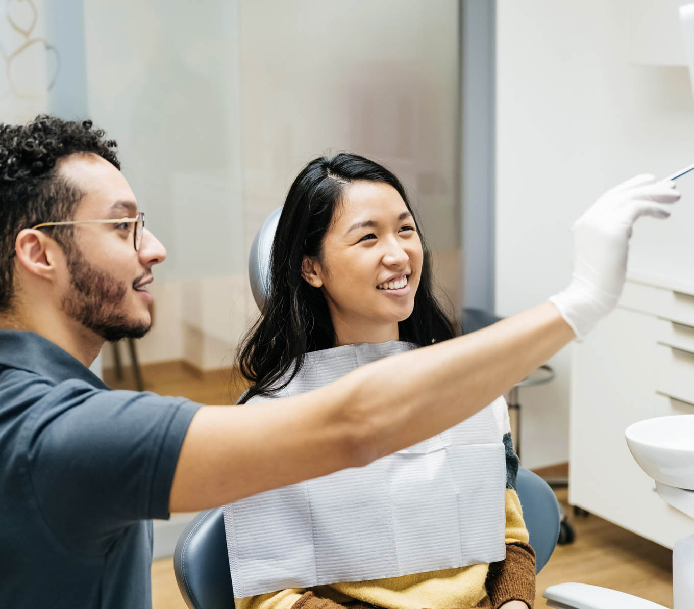 A young patient looking at a monitor and talking to her dentist about her dental health during a check up at his clinic.