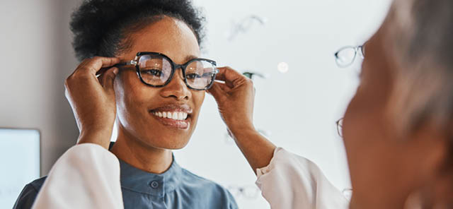Glasses check, black woman and customer with store worker and optician looking at lense. Eye consulting, smile and eyewear assessment in a frame shop for vision test and prescription exam for eyes