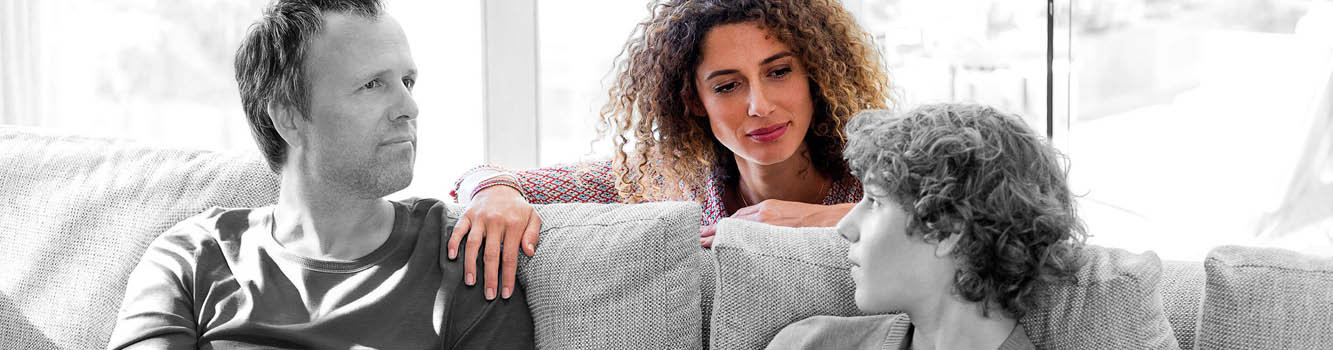 A man and a woman sitting on a couch. Description generated by AI