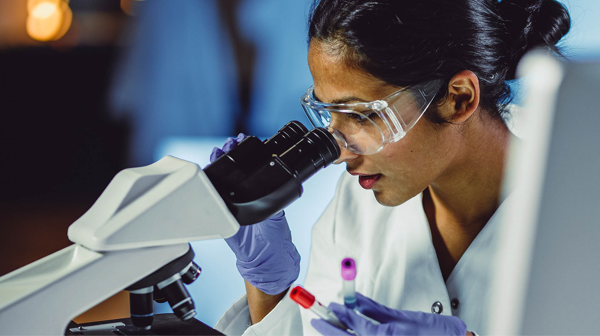 Photo of female scientist looking through a microscope