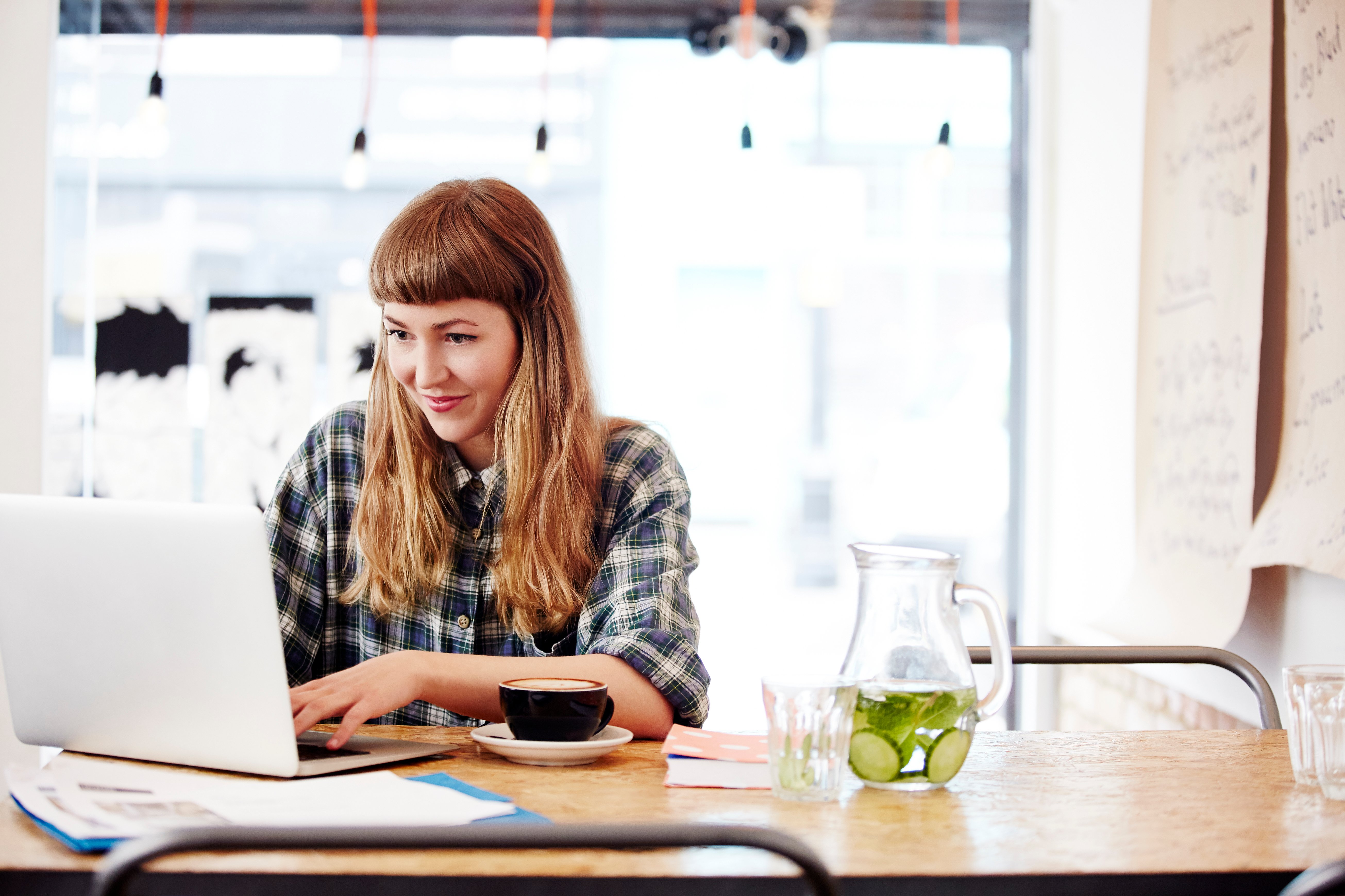Young woman sitting at table working on a laptop. 