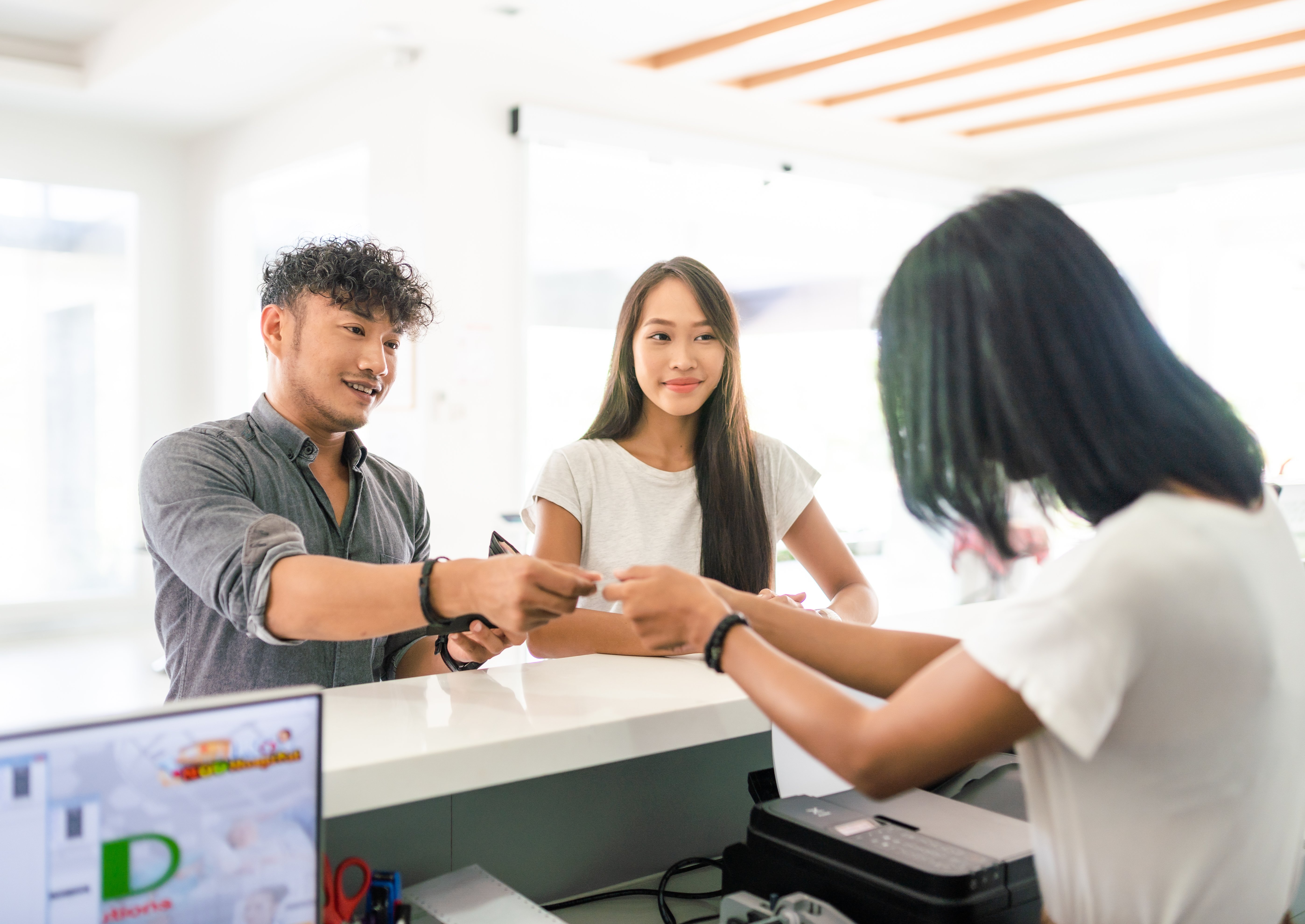 Man with woman standing beside him hands woman behind counter a credit card. 