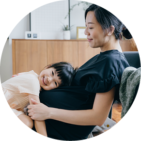 Lovely little Asian girl embracing her mother's pregnant belly, listening the heartbeat of her unborn sibling at home, looking at camera with smile. Sibling love. Welcoming a new family member with love and care concept