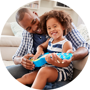 Toddler daughter sits on dad s knee playing ukulele at home